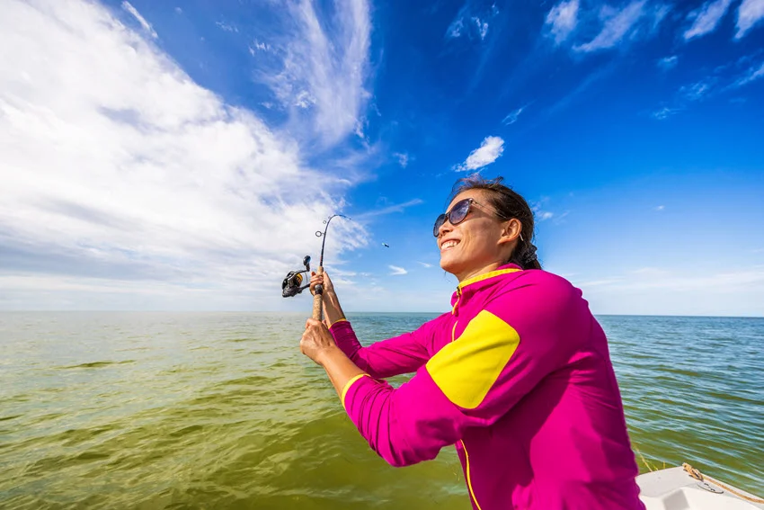 The fishing woman is having fun learning to fish by throwing a casting line somewhere in the Everglades.