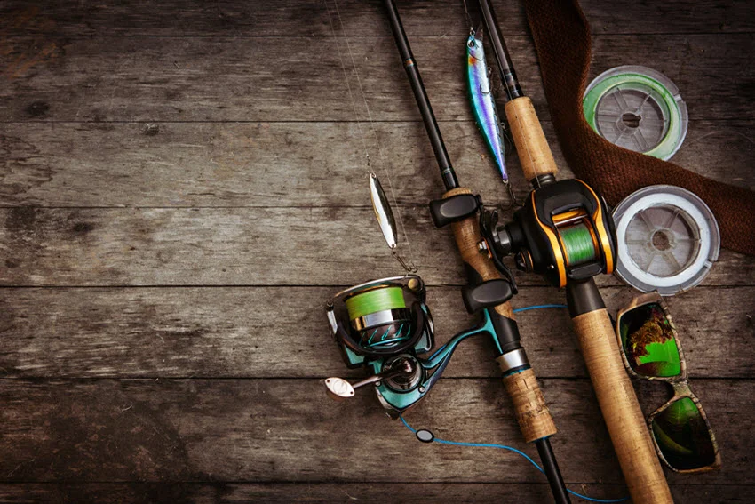 Assorted fishing tackle items such as lures, hooks, floats, and lines arranged on a wooden surface, creating a rustic and practical background for fishing enthusiasts.