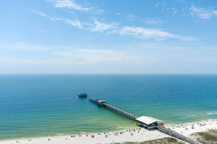 Aerial view of Gulf State Park Pier stretching out into the blue waters of the Gulf of Mexico.