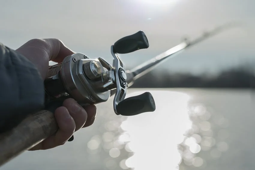 A man holding a rod with a baitcasting reel below the water surface.