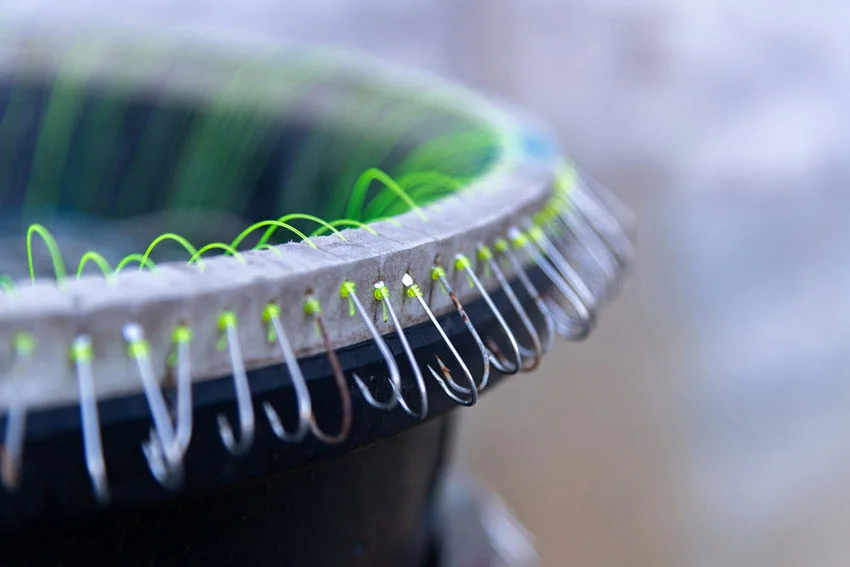 Close-up of fishing hooks and fishing line on the round wood basket.