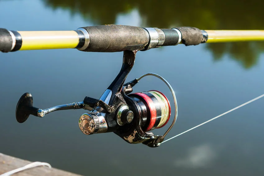 Focused shot of a fishing reel with calm water in the background.