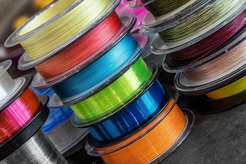 Close shot of different types of fishing monofilament and braided cords on fishing reels.