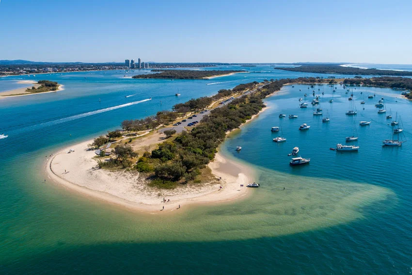 Aerial view of the Spit at Gold Coast, Australia, showing a marina with ships and boats docked along the golden sandy shoreline.