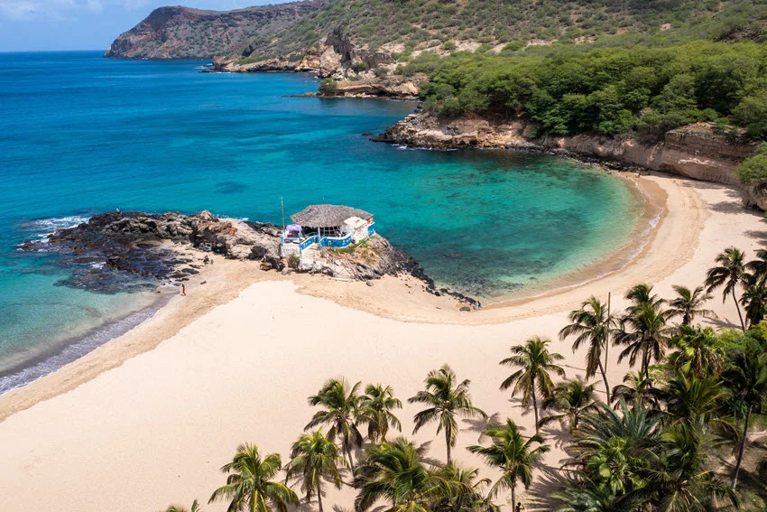 Aerial view of Tarrafal Beach on Santiago Island in Cape Verde, showing turquoise waters, sandy shorelines, and surrounding rocky hills.