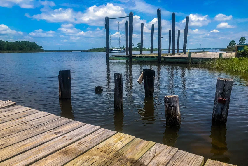 Fishing pier on the Pascagoula River on a bright, sunny day, with clear blue skies overhead and the river's calm waters gently flowing beneath the dock.