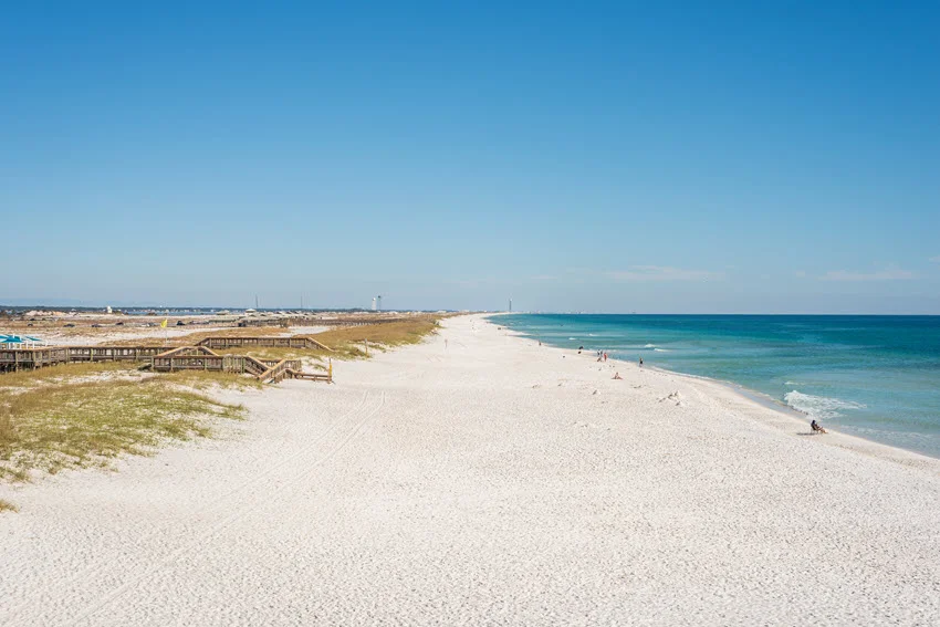 Panoramic view of Navarre Beach featuring a bright blue sky and stretches of white sand along the coastline.
