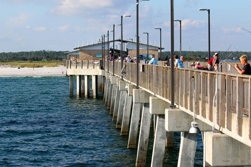 View from the end of Gulf State Park Pier looking back toward the beach with anglers fishing along the railings.