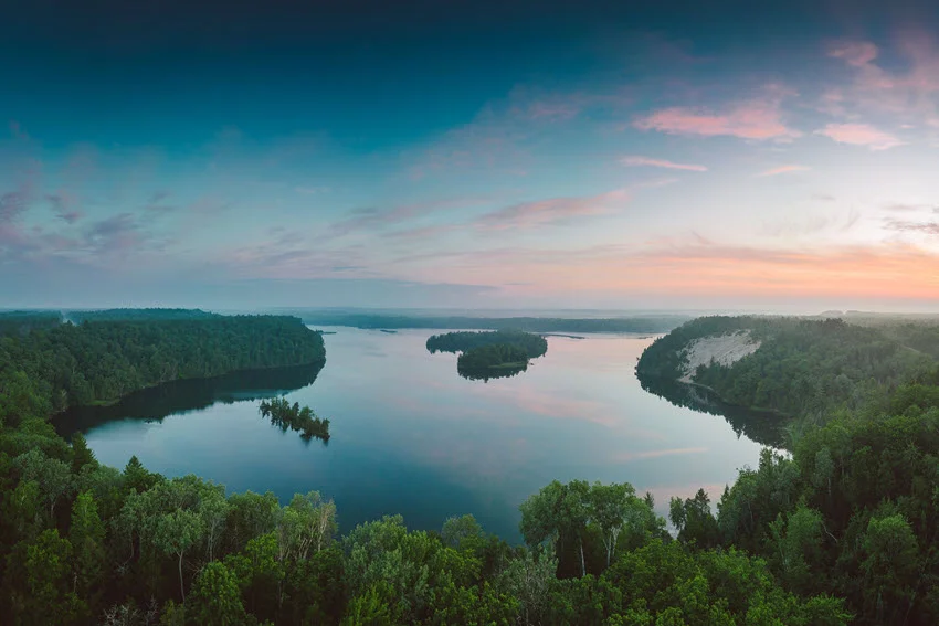 Panoramic aerial view of Lake Gogebic, Michigan, at sunset, with forested islands and calm water beneath a colorful northern sky.