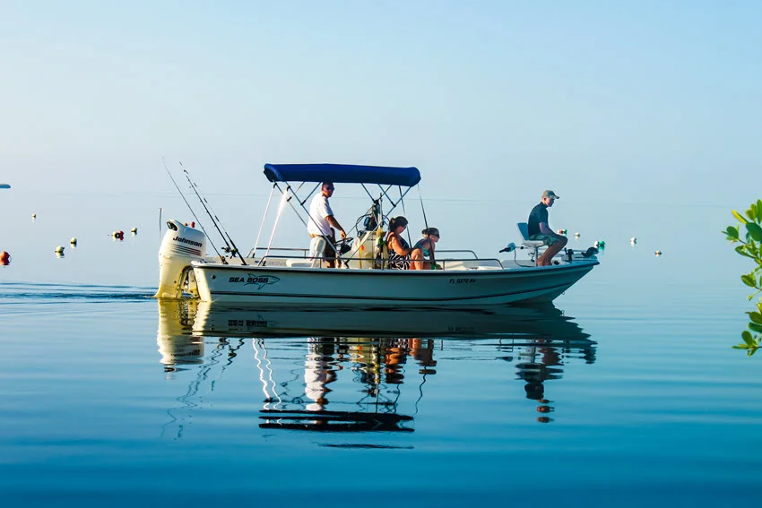 A family of four sits calmly on a drifting fishing boat somewhere in the ocean waiting for fish to bait.