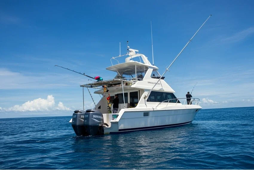 A view of a private fishing charter boat in offshore Gulf waters on a sunny day, surrounded by calm, deep blue seas and a clear sky.