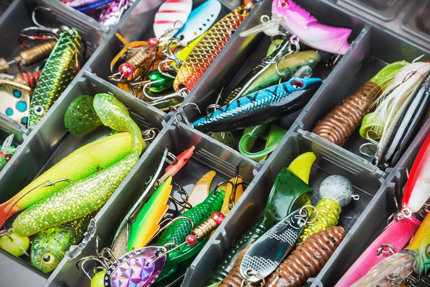 Fishing lures and accessories arranged in a box, with the focus centered on a specific bait. A close-up showcasing various tools for an optimal fishing experience.