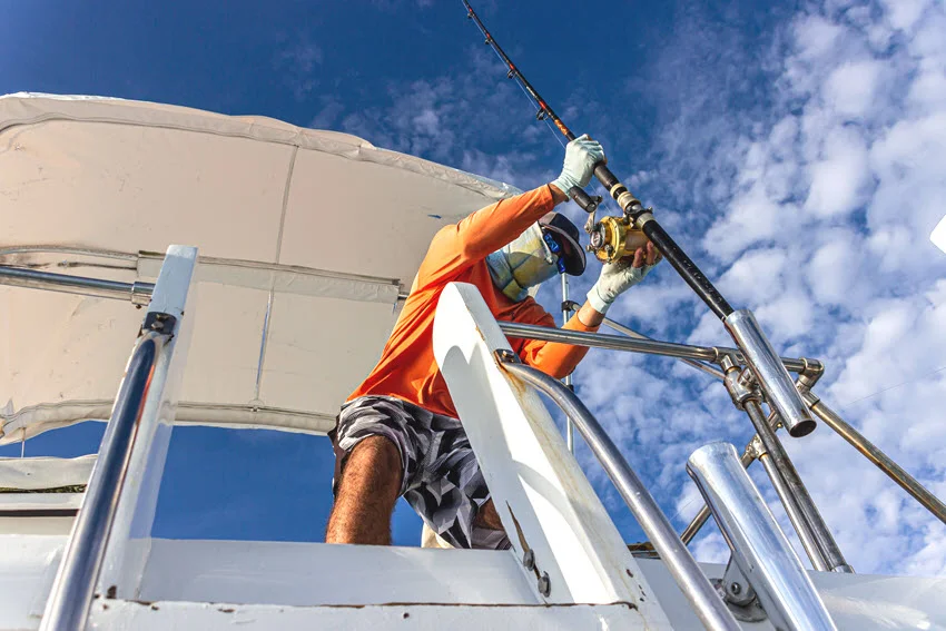 Captain on a fishing boat preparing heavy tackle and rod setup under a bright Florida sky before heading out for a saltwater fishing trip.