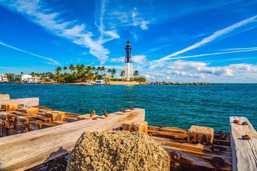 View of Hillsboro Inlet Lighthouse near Fort Lauderdale, Florida, with blue water, palm trees, and a coastal setting known for saltwater fishing access.