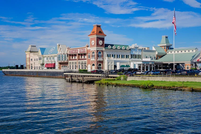 Boomtown Casino stands along the waterfront in Biloxi, Mississippi, with a red clock tower, colorful facades, and rippling water in front.