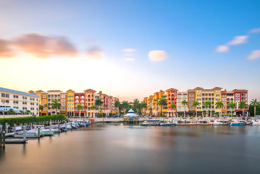Downtown Naples, Florida skyline at dusk with glowing city lights and a peaceful coastal atmosphere.