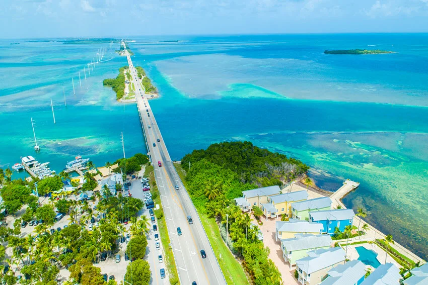Aerial view of the Seven Mile Bridge in the Florida Keys, stretching over turquoise flats and connecting small islands.