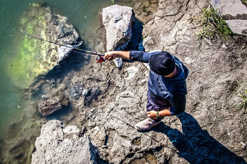 Angler shore casting from rocky structure into deeper water, a practical approach for covering Salmon travel lanes along drop offs.