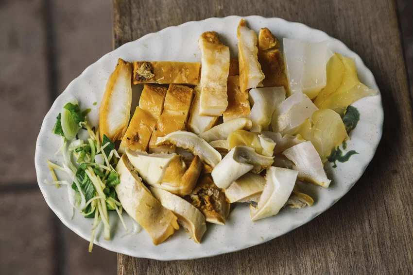 Slices of baked Sawshark fillets, placed on a big white plate, with herbs and lemon.
