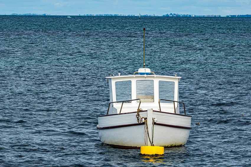 White, smaller sized fishing boat, drift offshore, in a deep blue waters.