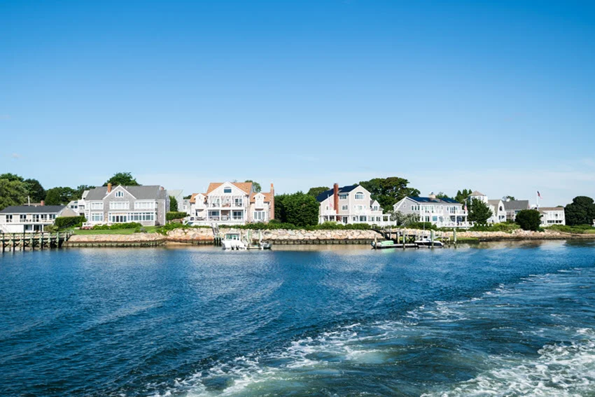 Coastal view of boats, beachfront homes, and calm water around Cape Cod, Massachusetts, a well-known region for nearshore Shark fishing.
