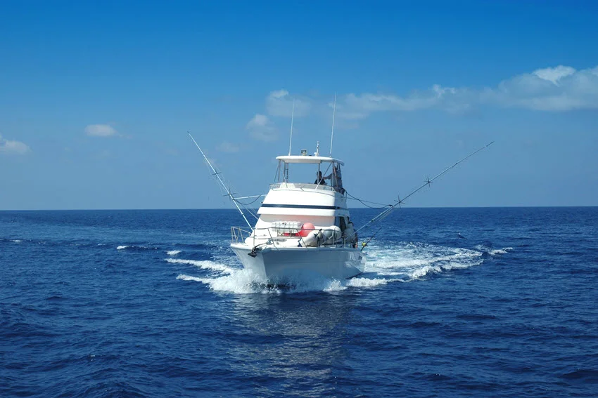 Sport-fishing boat traveling across open ocean water with outriggers raised, prepared for an offshore game or Shark fishing trip.