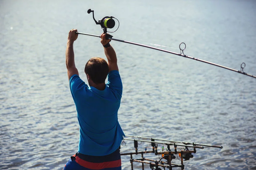 Angler casting spinning tackle over calm coastal water while targeting structure-loving fish like Sheepshead near bridges, piers, and shoreline habitat.