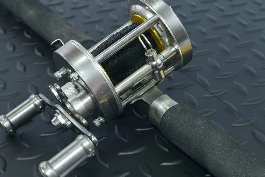 Close shot of a baitcasting reel resting on a metal surface, showcasing its detailed components.