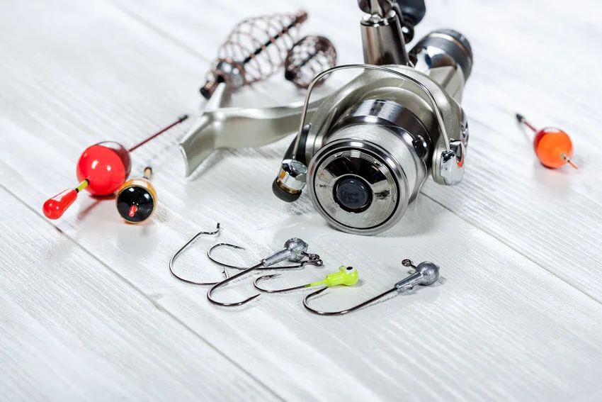 Basic fishing accessories, including hooks, are placed on a white wooden table.