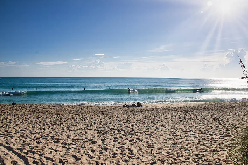Quiet Florida beach shoreline in bright morning light with gentle surf, matching the low-light conditions many anglers look for along the surf line.