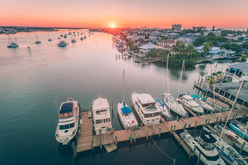 Aerial view of the Fort Myers, Florida waterfront marina at sunrise, with boats lined along the docks and calm inshore water that creates prime structure, shade, and current edges for coastal fishing.