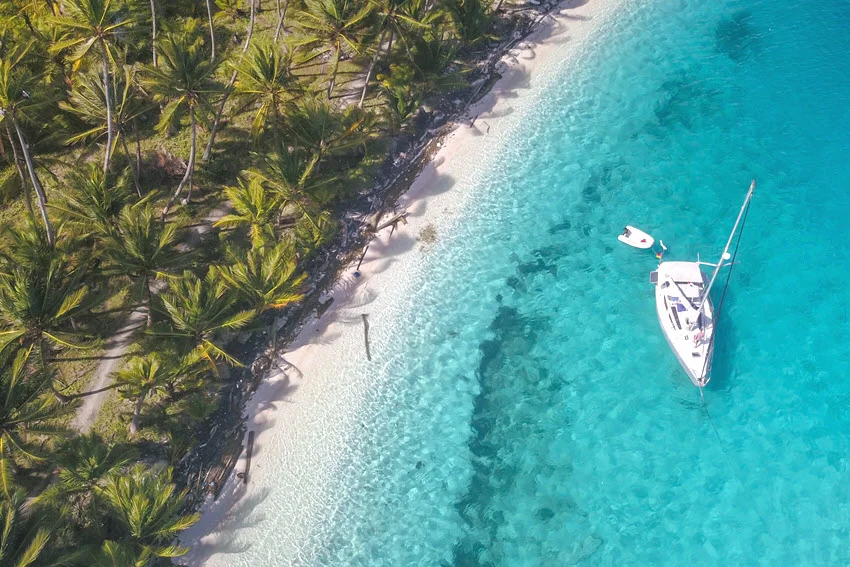 A small boat cruising along a bright Panama tropical coastline, showing clear-water edges, points, and shoreline breaks anglers often work when covering ground in warm coastal conditions.