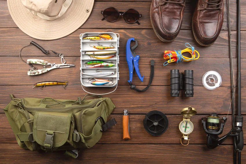 Organized Snook fishing gear laid out on a wooden surface, including a lure box, pliers, line, reel, and small tools for rigging and quick adjustments before heading to the water.