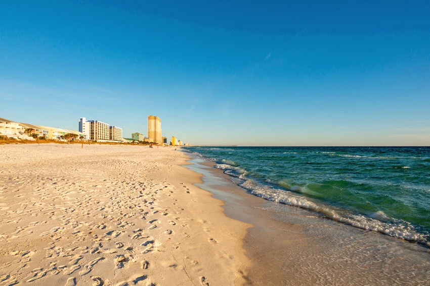 Sunny Florida Panhandle beach with gentle surf and open shoreline, a productive area for Spanish Mackerel from shore, piers, and nearshore waters.