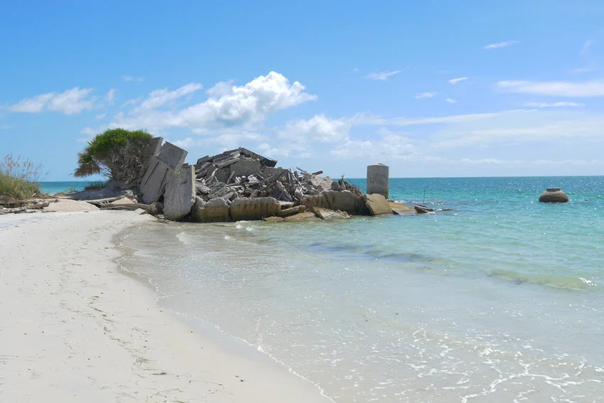 A view of a sandy beach on Egmont Key with scattered rocks, calm turquoise waters, and a bright sunny day.
