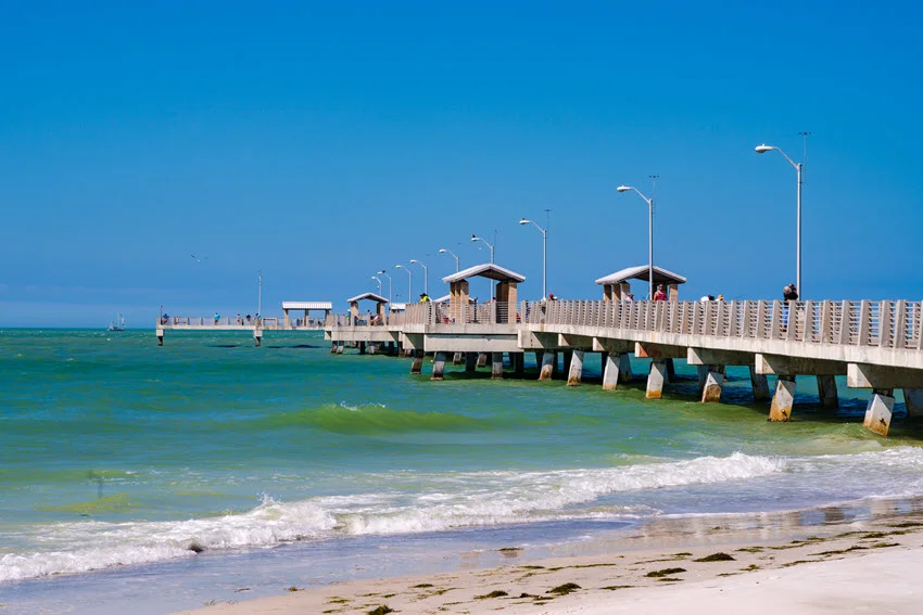 A view of a fishing dock in Fort De Soto Park, surrounded by calm waters and lush greenery.