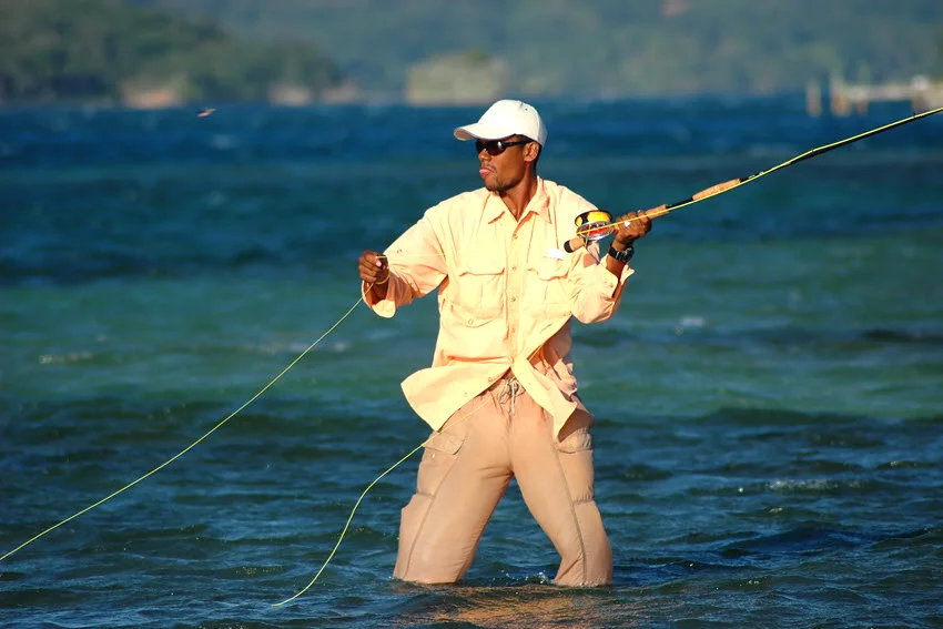On a sunny, bright day, an angler performs sight fishing in the shallow ocean.