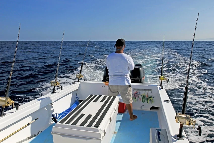 Angler standing on a deep-sea fishing boat surrounded by calm blue waters during a big game adventure.