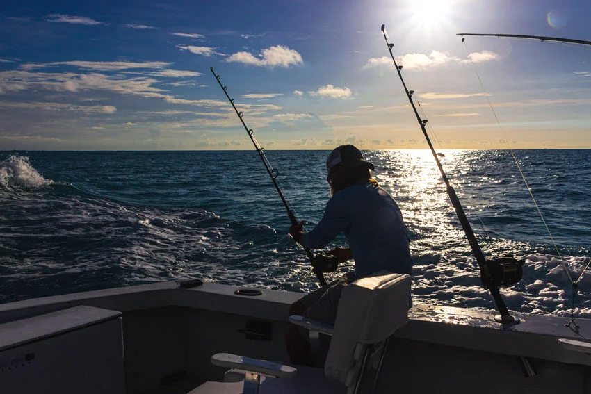 Angler preparing fishing rods at sunset during a charter trip off Key West.