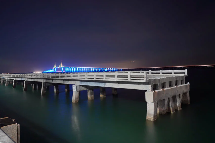 Night view of the illuminated Skyway Fishing Pier State Park extending into the calm waters.