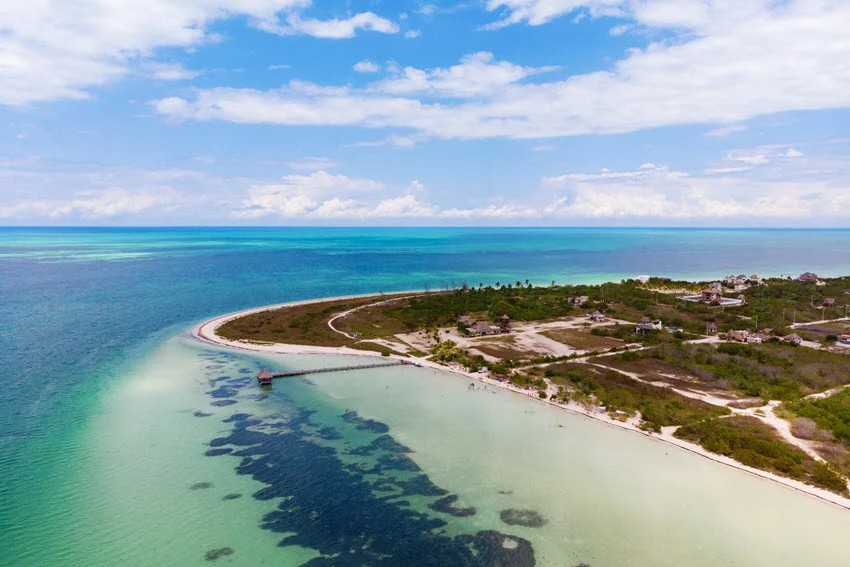 Aerial view of Punta Cocos, a remote and scenic beach area on Isla Holbox, Mexico, with turquoise waters, white sandy shoreline, and lush greenery.