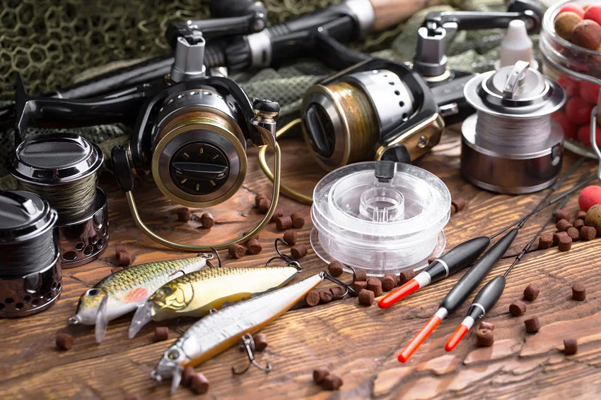 Spinning rods and reels along with various sport fishing items arranged on an old rustic background, showcasing essential gear for anglers.