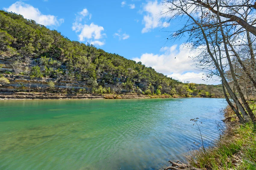 Panoramic shot of the Guadalupe River surrounded by lush vegetation in Texas.