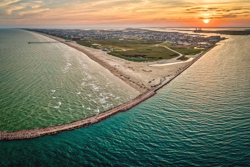 Aerial view of Port Aransas bathed in the breathtaking colors of a sunset, with the coastline glowing in the evening light.