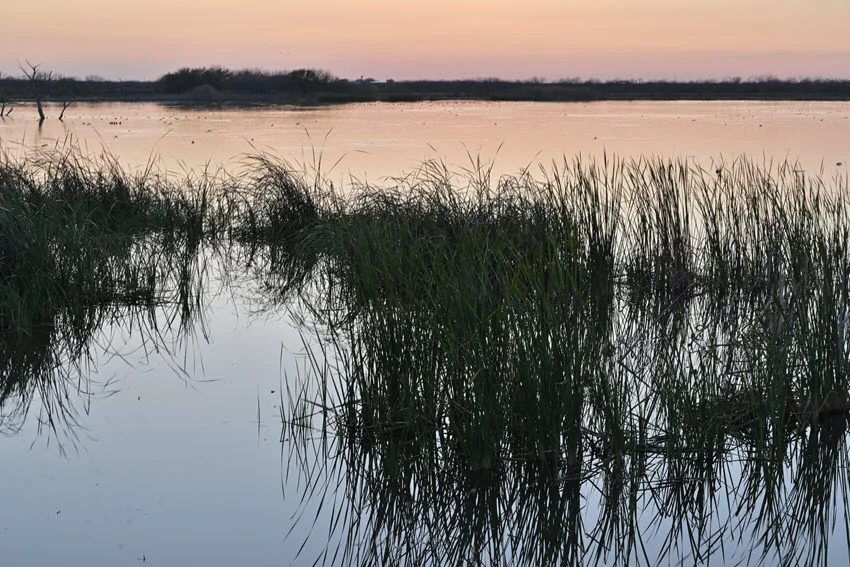 Sunset over the water of Choke Canyon Reservoir, reflecting the fading light of the evening sky.