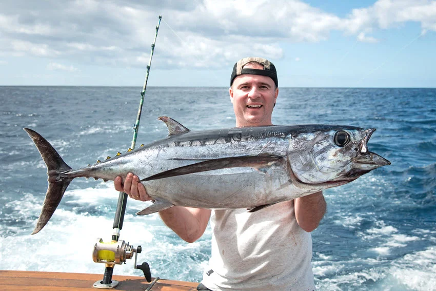 Angler holding a Tuna on an offshore boat after a successful deep sea catch.