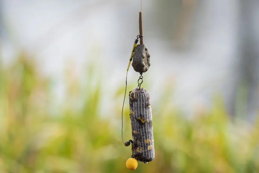 Close-up shot of a fishing rig hanging from a hook, with a blurred, grassy background for contrast.
