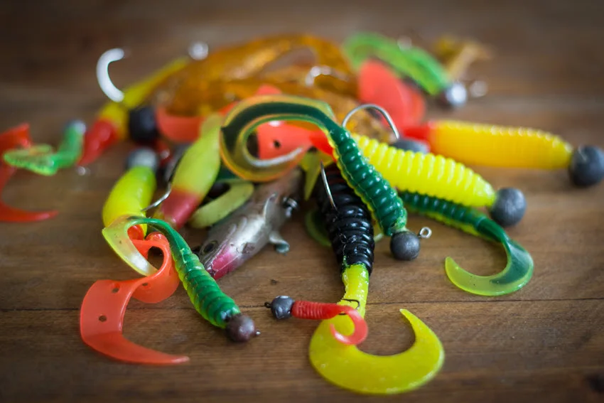 Different types of silicone lures placed on wooden surface.