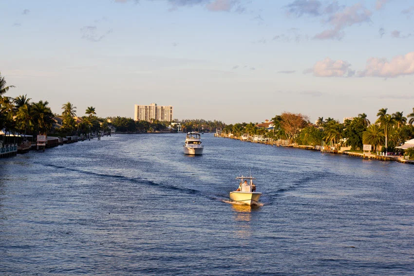 Wide shot of fishing boats on the Intracoastal Waterway at sunset, with warm hues reflecting off the calm water and creating a serene atmosphere.
