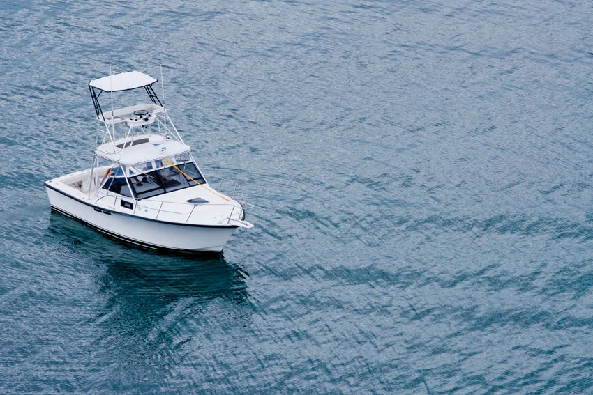 Aerial view of a fishing charter gliding slowly on open water.